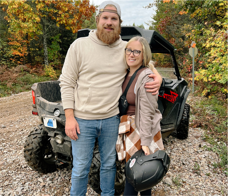 A couple smiling in front of their atv